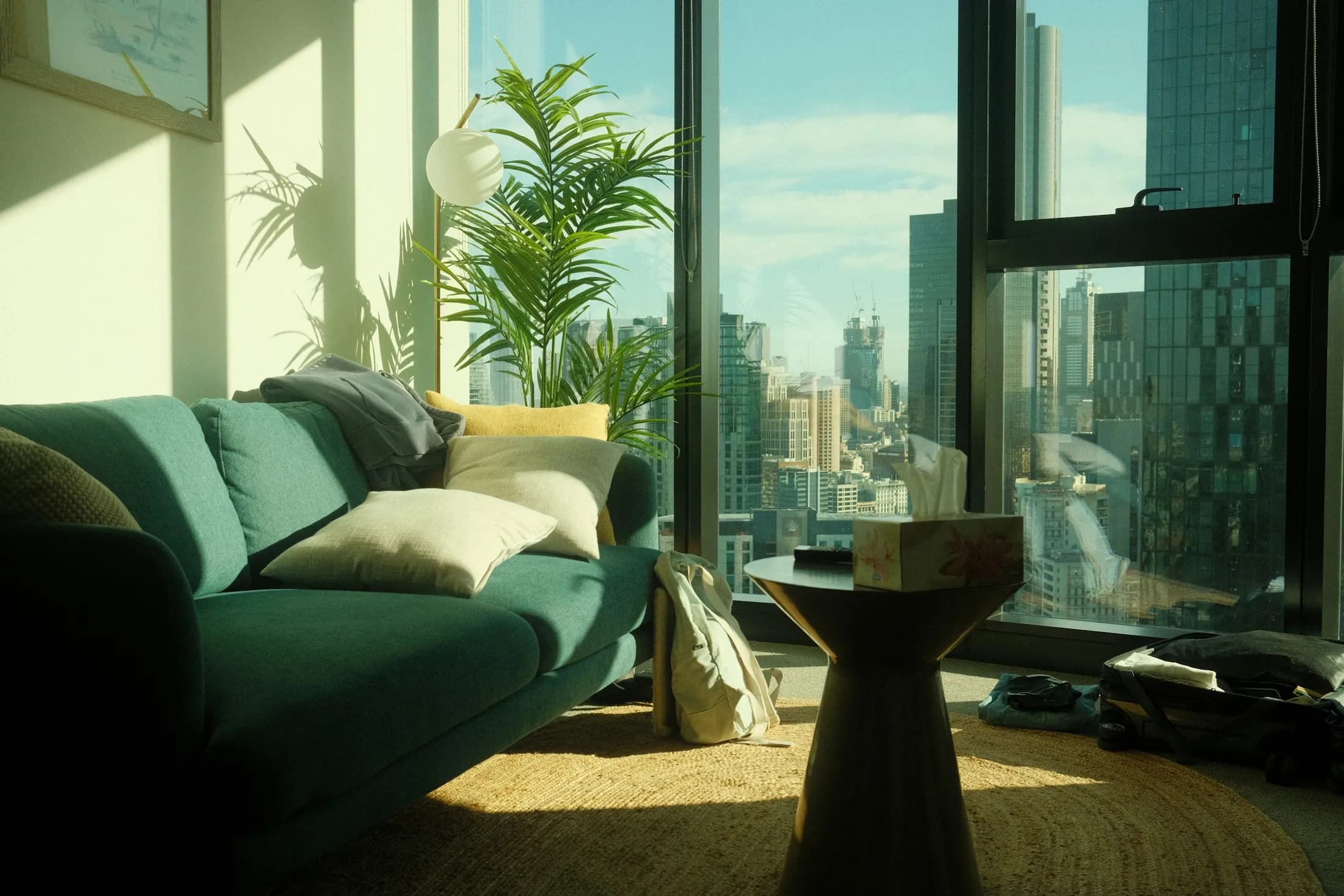 An apartment living room with a green sofa beside tall windows