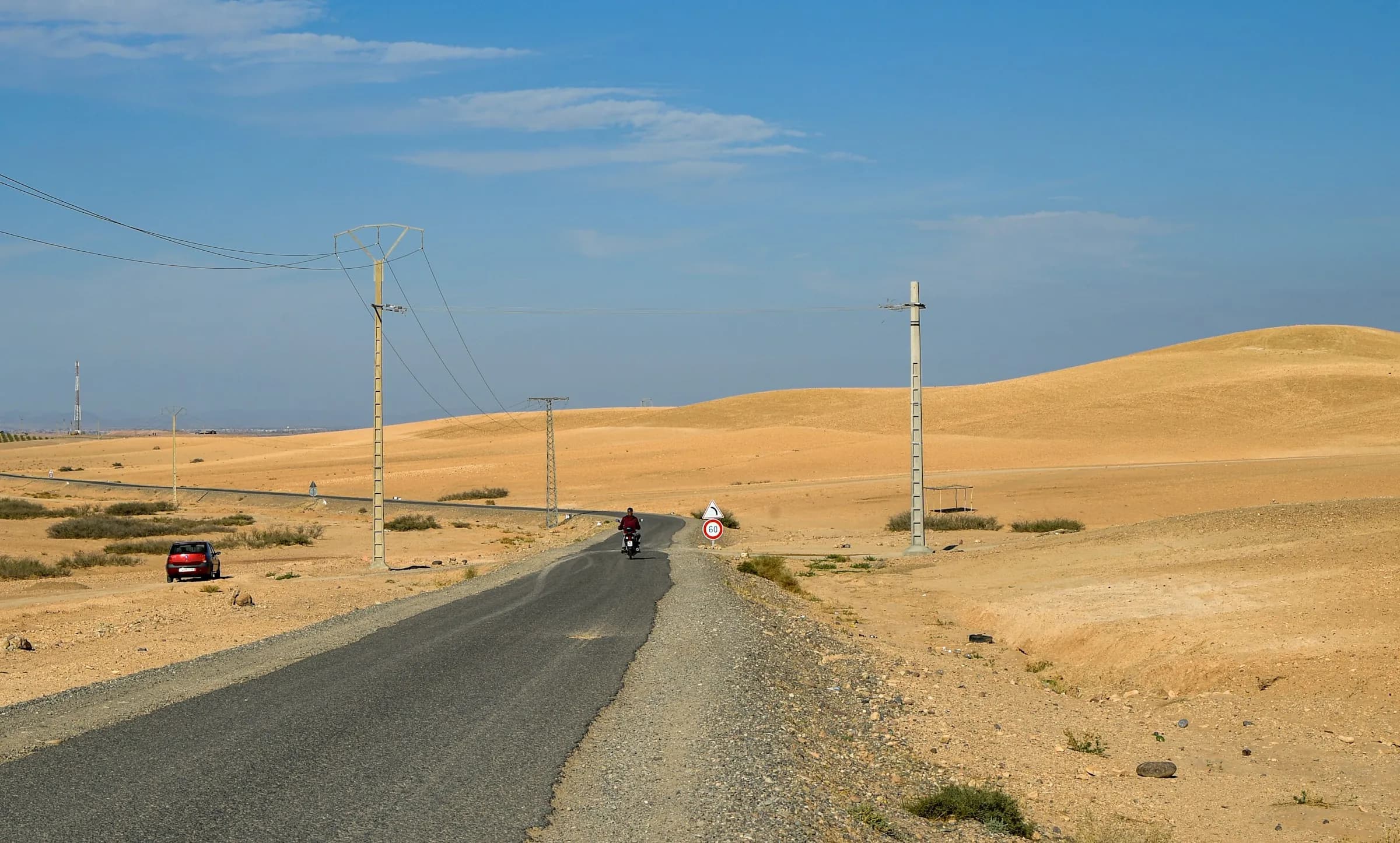 A road through open desert with sand stretching away on both sides