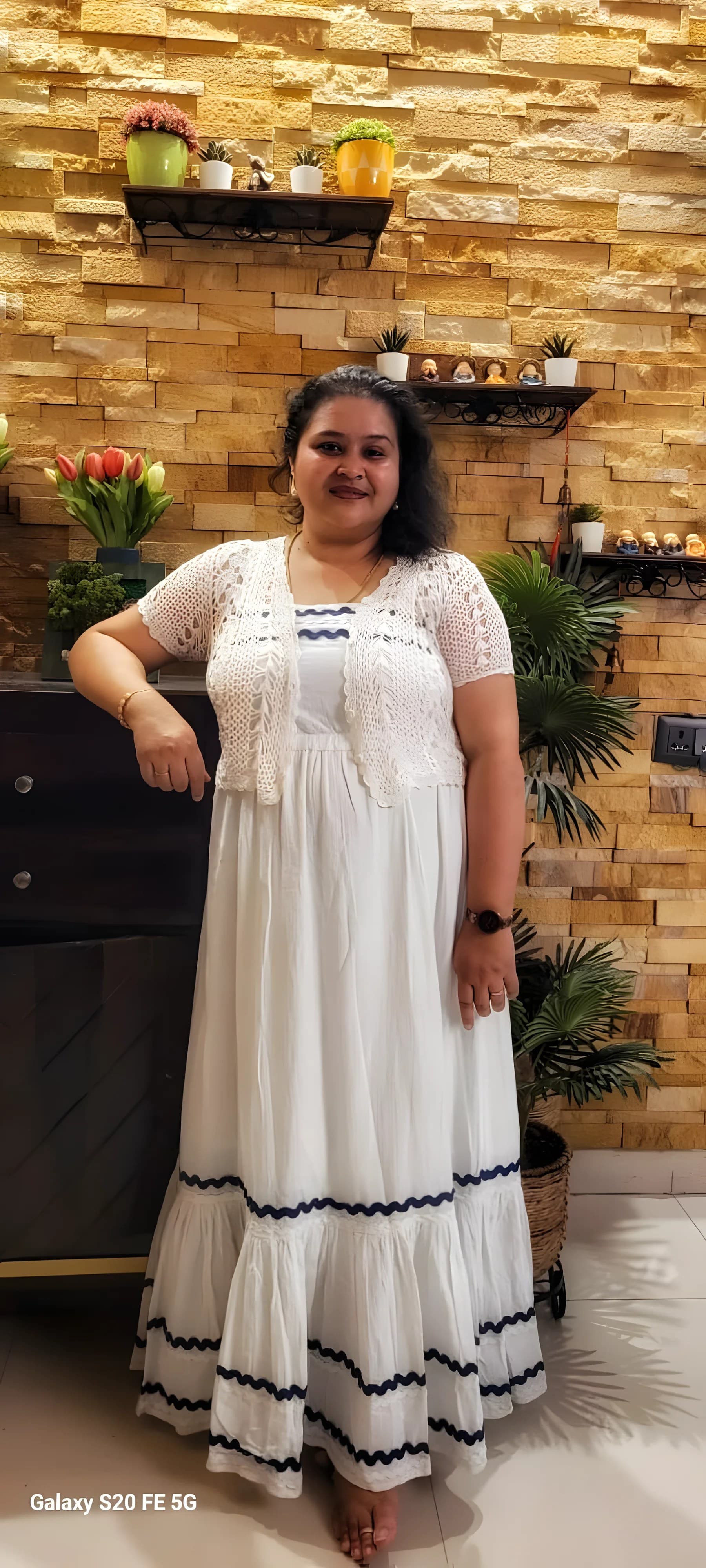 Barsha Prakash standing in front of a stone wall lined with plants